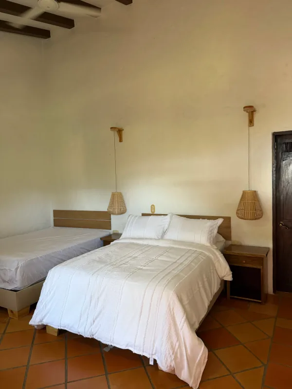 Habitación doble en suite de La Juana con dos camas y lámparas artesanales