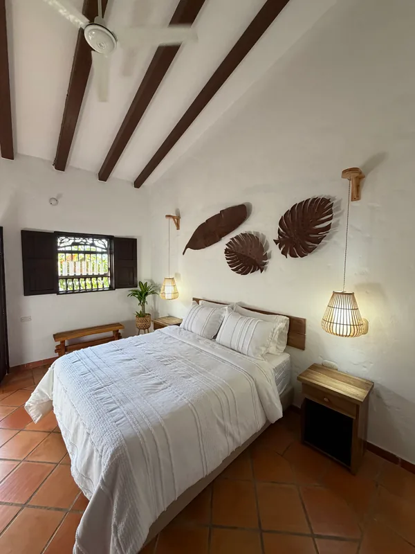 Habitación privada de La Juana con cama doble, decoración artesanal y ventana colonial