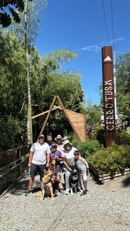 Familia y visitantes con sus mascotas en el tótem oficial de entrada al Parque Comfama