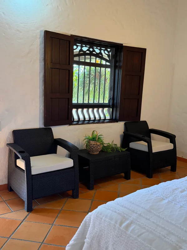 Rincón de descanso interior y ventana colonial tallada en una suite de La Juana
