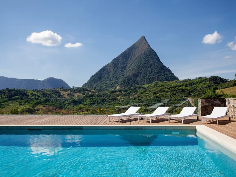 Pool terrace at a luxury finca in Antioquia with views over a green valley and the rocky peak, loungers and blue water