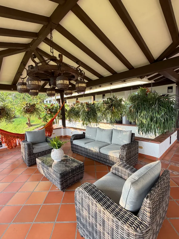 Kiosco y sala social campestre de La Juana Cerro Tusa con hamaca, muebles de descanso y helechos colgantes