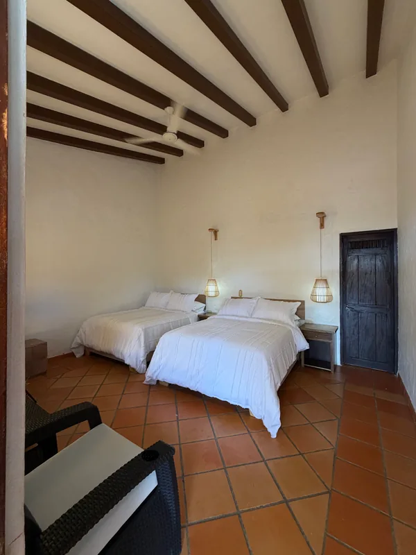 Habitación suite de La Juana Cerro Tusa con dos camas, techos altos con vigas de madera y acabados tradicionales